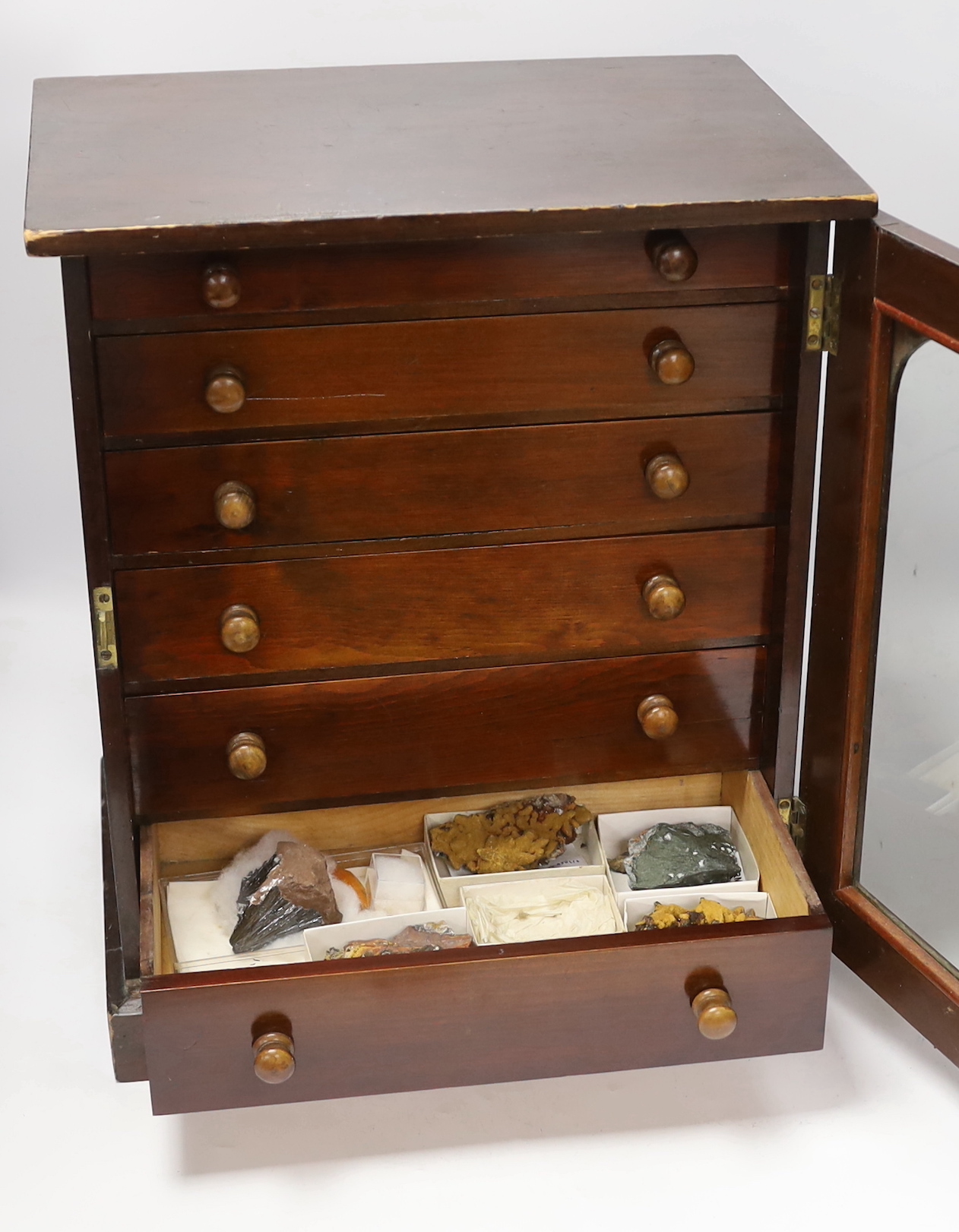 An early twentieth century six drawer pine collector’s cabinet of mineral and crystal samples including; Amber and insects in amber, Baryteson Calcite, Aplite, Nodular Rhyolite, Desert Roses, etc. many specimens with lab